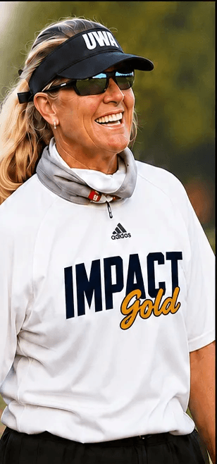 Coach Carie Dever Boaz on the field, smiling, wearing a visor and sunglasses